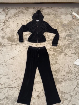 Svart velourset från Juicy Couture - Svart Juciy couture set, knappt används , byxan är 10/11 i storlek och tröjan är 13/14. På byxans snöre så är en av metallen bort 