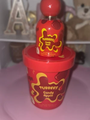 Tubbees Candy Apple parfym - Parfymen Tubbees Candy Apple kommer i en färgglad röd flaska med gula detaljer och rund kork. Doften är inspirerad av söt karamelläpple och flaskan har en lekfull design som sticker ut på hyllan. Perfekt för dig som gillar fruktiga och söta dofter.