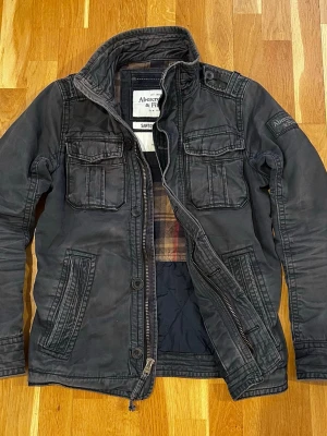 Abercrombie k& Fitch Sawtooth Fieldjacka - Galet snygg fieldjacka från Abercrombie & Fitch | Tvättad grå färg med en sjukt fin naturlig patina | Äldre modell | Hög kvalitet |Distressing som tillhör designen | Storlek S, men passar även M | Mycket gott skick (se bilder)   Hör av er vid ytterligare frågor!