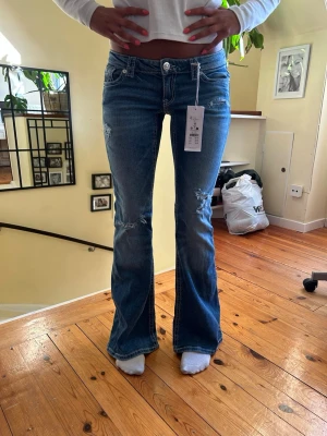Blå low waist bootcut jeans  - Snygga blå lågmidjade bootcut jeans från Gina med slitna detaljer och låg midja. Jeansen är lite stretch i storlek M 14+ men skulle säga att de är storlek S. Perfekta för en trendig och avslappnad look. Godkänner prisförslag vid snabb affär!💕