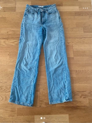 Wide jeans i ljusblå denim - Säljer ett par ljusblå wide jeans från Winnie Rigid i modellen 26/32. Jeansen har hög midja, raka och vida ben samt klassiska fem fickor. Tillverkade i 100% denim för en cool och avslappnad look.
