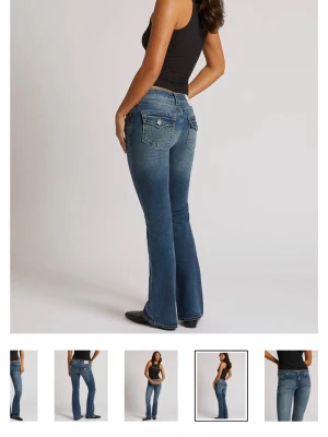 Blå bootcut jeans från True Religion - Snygga blå bootcut jeans från True Religion med klassiska kontrastsömmar och dekorativa fickor bak med lock och knappar. Jeansen har mide midja och är tillverkade i denim med lätt stretch för en bekväm passform och i storlek(25)