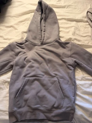 Ljusgrå hoodie från Maggiore - Säljer en stilren ljusgrå hoodie från Maggiore i storlek S. Hoodien har en stor huva, magficka och ribbade muddar vid ärmslut och nederkant. Tillverkad i mjukt och skönt material som känns riktigt cozy. Perfekt för dig som gillar en clean och enkel look.