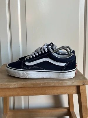Marinblå Vans Old Skool sneakers - Klassiska Vans Old Skool sneakers i marinblått med vit sula och vit sidostripes. Skorna har vita snören och detaljer i mocka och canvas. Bara att skriva vid funderingar