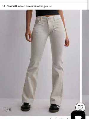 Vita flare jeans med fickor - Snygga vita flare jeans med hög midja och stora framfickor. Jeansen har utsvängda ben och dekorativa bakfickor med lock och knapp. Perfekta för en trendig och avslappnad look.