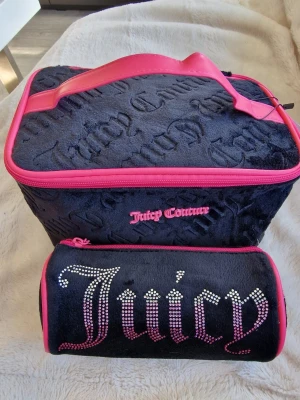 Juicy Couture svart och rosa necessärset - Juicy Couture necessärset i svart plysch med rosa detaljer. Stora väskan har präglad logga och rosa dragkedja, mindre cylinderformad väska med strassbokstäver och rosa kant. Perfekt för smink eller småprylar.