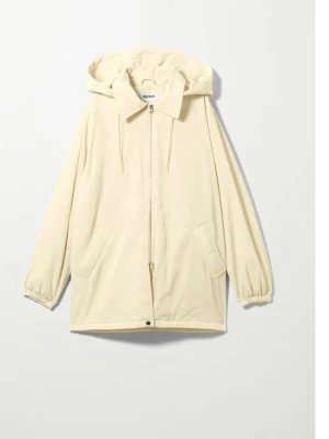 Beige vindjacka med huva från Weekday - Stilren beige vindjacka från Weekday med dragkedja framtill, två snedställda fickor och justerbar huva. Jackan har elastiska muddar vid ärmsluten och en rak, avslappnad passform. Perfekt för blåsiga dagar.