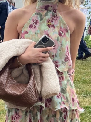Blommig halterneckklänning från Gina Tricot - Superfin kort blommig klänning från Gina Tricot med halterneck och volangdetaljer. Klänningen har pastelliga toner i grönt, rosa och lila, samt ett lager-på-lager-utseende. Perfekt för sommarens alla tillfällen!