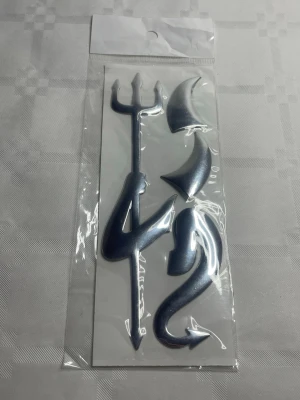 Djävulstillbehör i silver för maskerad - Ett set med djävulstillbehör i silverfärgad plast, perfekt för maskerad eller cosplay. Innehåller en treudd, horn och en svans. Allt är förpackat i en genomskinlig plastpåse. Snyggt och enkelt sätt att komplettera din bil outfit.