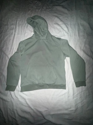 Grön Jack & Jones Hoodie - En stilren grön hoodie från Jack & Jones som kombinerar komfort och enkel streetstyle. Den är tillverkad i mjukt och slitstarkt material som känns skönt mot huden och håller formen även efter många tvättar. Huvan är justerbar med dragsko och ger en avslappnad look, perfekt för både vardag och fritid.