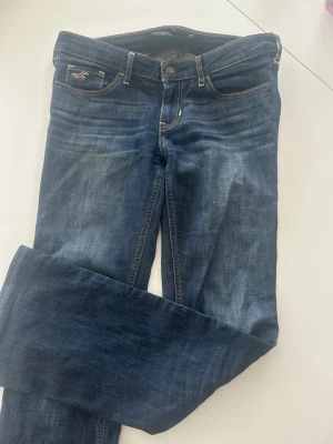 Lågmidjade hollister jeans - Snygga mörkblå jeans från Hollister med låg midja. Knappt använda. Dem är insydda i midjan men går att ta bort. De är även uppsydda längst ner. Passar mig som är 163 på gränsen ungefär. Storleken är W27, L31.