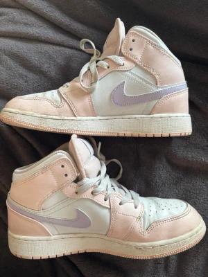 Nike Air Jordan🫶🏻 - Säljer ett par Nike Air Jordan 1 Mid sneakers i pastellfärger. Skorna har en ljusrosa och vit ovandel i läder med en ljuslila swoosh på sidan. Klassisk siluett med högt skaft och perforerad tåbox. Perfekta för dig som gillar stilrena och trendiga sneakers. Super snygga orginalbox kommer med!!💘