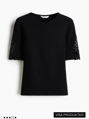 Svart topp med spetsdetaljer - Stilren svart topp med halvlånga ärmar och snygga spetsdetaljer på ärmarna. Rak passform och rund halsringning. Perfekt för dig som gillar en enkel men ändå elegant look.