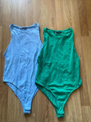 Blå och grön ärmlös body Zara - Två stilrena bodys från Zara i färgerna ljusblå och grön. Båda är ärmlösa med rund halsringning och har en tight passform. Perfekta att matcha med jeans eller kjol för en enkel och snygg look.