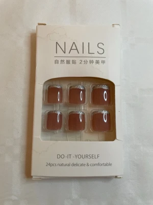 Bruna press-on naglar med glitter - Säljer ett set med 24 press-on naglar i brun nyans med silverglittrig kant. Naglarna har en fyrkantig form och ger en elegant look. Perfekta för dig som vill fixa snygga naglar snabbt och enkelt hemma.
