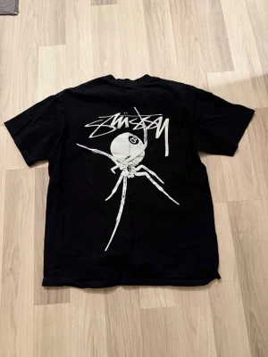 Svart Stüssy t-shirt med spindeltryck - Svart t-shirt från Stüssy med stort vitt spindeltryck och logga på ryggen samt liten logga på bröstet.💓💓