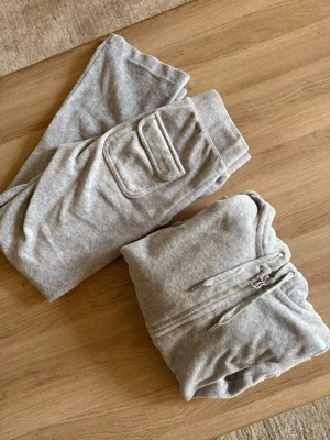 Juicy Couture - Använd fåtal gånger, hylsorna på byxornas snören har lossnat. Kan skickas med om man vill försöka limma fast igen, förövrigt bra skick! Byxorna är uppsydda, passar någon som är 150-154 cm lång. Storlek XXS på båda delarna.