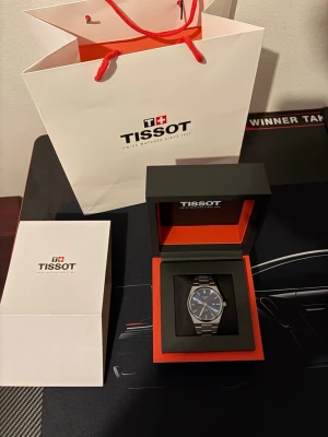 Tissot PRX Blå urtavla – Full set med box & papper – Mycket fint skick - Säljer en stilren och eftertraktad Tissot PRX med snygg blå sunburst-urtavla och integrerat stålarmband. En tidlös schweizisk design som passar både vardag och finare tillfällen.  Klockan är i mycket fint skick och levereras som full set: ✔ Originalbox ✔ Tissot påse  ✔ Safirglas ✔ Swiss Made ✔ Bekväm och tunn profil på handleden  En populär modell som håller värdet bra – perfekt för både samlare och daglig användning.
