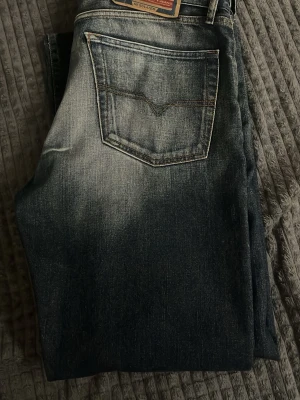 Diesel jeans - Säljer ett par mörkblå diesel jeans med en snygg tvätt. Använt bara några gånger och en av dem så gick flärpen sönder. Flärpen där bak är sönder men det syns inte om man har bälte. Skriv om ni vill ha mått eller om ni har några frågor. Priset är inte satt.