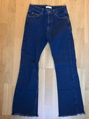 Full length flare petite jeans - Ett par mörkblå full length flare petite jeans från Gina tricot i storlek 32. De har en innerbenslängd på ca 65-70cm då jag klippt av dem. Skriv för mer info.