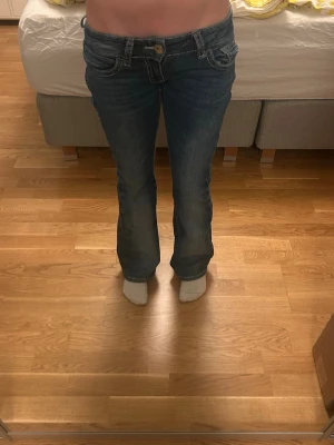 Blå bootcut jeans med broderad ficka - Säljer ett par blå bootcut jeans från Gina  med låg midja och snygga broderade detaljer samt paljetter på bakfickan. Jeansen har klassisk femficksmodell och kontrastsömmar. De har bara andvänds en eller två gånger och ser som nya ut. Är storlek xs. Pris kan diskuteras🤗💝