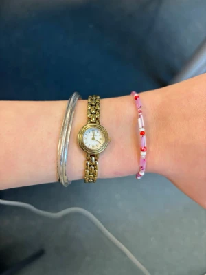 Rosa och rött pärlarmband - Säljer ett handgjort armband med små pärlor i rosa, rött och vitt. Armbandet har både cylinderformade och runda pärlor och stängs med en metallhake. Perfekt för dig som gillar färgglada accessoarer och vill addera lite färg till din stil.