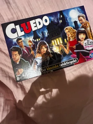Cluedo brädspel klassiskt detektivspel - Cluedo är det klassiska detektivsällskapsspelet där du ska lista ut vem som är mördaren, med vilket vapen och i vilket rum. Spelet har färgglad kartong med illustrationer av karaktärer och ett mystiskt hus. Passar för 2-6 spelare och ålder 8+. I ansvänt cluedo med bruxhandvisning