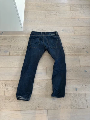 Mörkblå raka jeans från diesel - Säljer ett par mörkblå jeans från diesel med klassisk rak passform. Jeansen har fem fickor, orange sömmar och bälteshällor. Tillverkade i slitstark denim som ger en tidlös look. Perfekta för dig som gillar en enkel och clean stil.