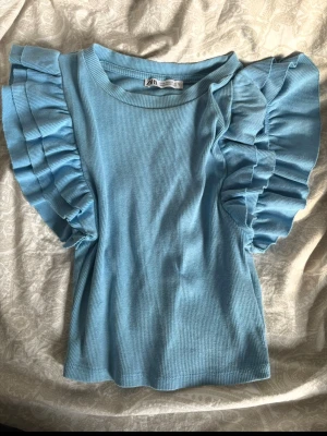Snygg topp - Snygg ljusblå topp från Zara med  volangärmar. Storlek S💗