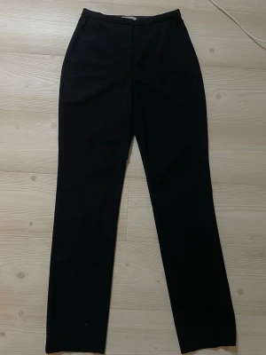 Mörkblå  raka kostymbyxor - Stilrena mörkblå kostymbyxor med rak passform och diskreta sidofickor. Byxorna har klassisk midja och stängs med dragkedja och hake. Perfekta för en clean och dressad look. Materialet är en mjuk och följsam textil. Sitter så snyggt!! 