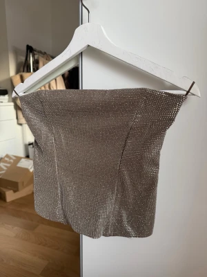 Glittrig brun tubtopp från Zara - Säljer en snygg brun tubtopp från Zara med glittrande stenar. Helt ny! 