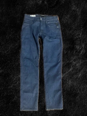 Mörkblå slim fit jeans Replay - W31, L30,  Säljer ett par mörkblå slim fit jeans från Replay, modell Anbass. Klassisk femficksdesign med snygga sömmar och bälteshällor. Jeansen är tillverkade i stretchigt denimtyg för extra komfort och har en modern passform som sitter snyggt.