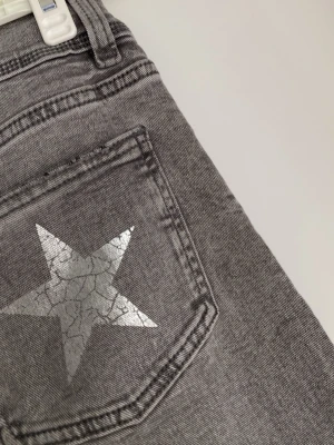 Grå jeans med silverstjärna - Snygga grå jeans med en stjärna på bakfickan. De är lågmidjade och i storlek 164 av Gina Young men de passar som xs också. 