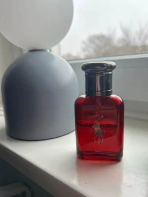 Röd parfymflaska från Ralph Lauren - 40ML på nypris 740kr ungefär Snygg parfymflaska från Ralph Lauren i en djup röd färg med silverfärgat lock. Flaskan har den klassiska Polo-loggan med ryttare på framsidan och RL-gravyr på locket. Perfekt som en stilren detalj på hyllan.proset är inte spikat än