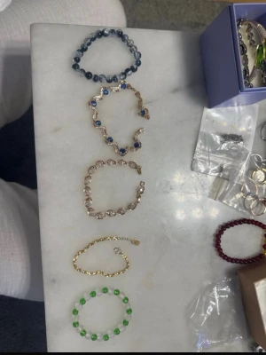 Grönt och transparent pärlarmband - Säljer ett elastiskt armband med växelvis gröna och transparenta pärlor. Armbandet har en enkel och stilren design som passar perfekt för att addera lite färg till din outfit. Pärlorna är runda och sitter på en elastisk tråd som gör det lätt att ta på och av.