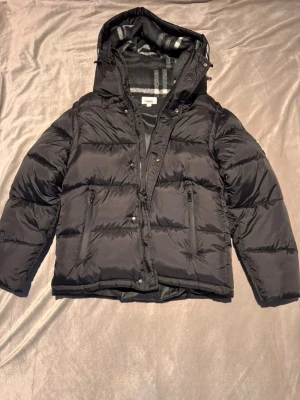 Svart Burberry pufferjacka  - Säljer nu en svin snygg Burberry jacka som även går att göra om till en väst och blir därmed flexibel till fler årstider! | Nytt skick alltså oanvänd | Passar storlek M skulle jag säga | Pris 1299, diskuterbart | Vid frågor är det bara att höra av sig! :)  
