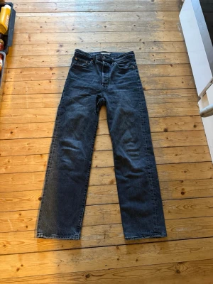 Svarta raka jeans från Levi's - Klassiska mörkblå jeans från Levi's med rak passform och 4 fickor. Jeansen har en enkel design med knappgylf och är tillverkade i slitstark denim. Perfekta för en avslappnad och tidlös stil.