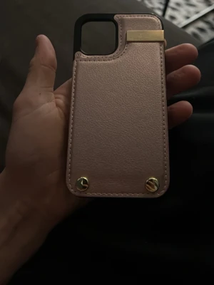 Rosa mobilskal med korthållare - Snyggt rosa mobilskal med inbyggd korthållare och guldfärgade detaljer. Skalet har en unik design med plats för flera kort och är gjort i konstläder med metalliska accenter. Perfekt för dig som vill ha både stil och funktion i ett.