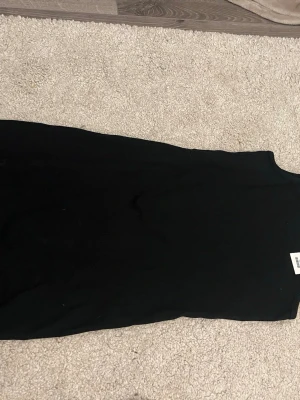 Svart ribbad klänning från 157 med prislappen kvar aldrig använd - En enkel och stilren svart ribbad klänning från 157. Klänningen är ärmlös och har en rund halsringning. Perfekt för dig som gillar minimalistisk stil och vill ha något bekvämt och snyggt.