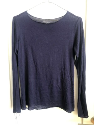 Mörkblå långärmad topp från & Other Stories - En enkel och stilren mörkblå långärmad topp från & Other Stories. Toppen har rund halsringning och är gjord i ett tunt, mjukt material som känns skönt mot huden. Perfekt att styla lager på lager eller bära som den är. M fast passar mindre 