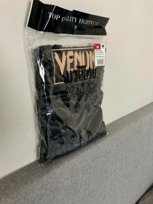 Venum Shorts Svart/Guld - Helt nya snygga Muay Thai shorts från Venum i svart med guldfärgade detaljer och logga framtill. Tillverkade i lätt och slitstarkt material som passar perfekt för träning och sparring. Klassisk passform med elastisk midja för bästa komfort. Ord pris: 500 + 50kr frakt. Storlek M