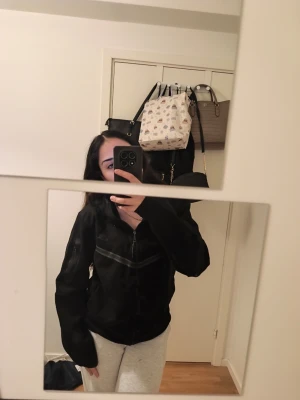 Svart hoodie från Nike med dragkedja - Säljer en svart hoodie från Nike i storlek M. Hoodien har dragkedja framtill, två sidofickor och en klassisk huva. Tillverkad i mjukt material som passar perfekt för chill dagar eller träning. Enkel och stilren design med diskret Nike-logga.