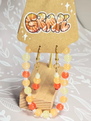 Paket: armband och Färgglada pärlörhängen i orange och gult - Unika örhängen med pärlor i olika nyanser av orange, gult och vitt. Matchande pärlarmband, 18 cm långt. Pärlorna är runda och sitter på guldpläterade krokar. Perfekta för dig som vill ha ett färgglatt och lekfullt smycke som sticker ut. Handgjorda och riktigt trendiga!