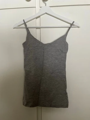 Grå linnetopp från 157 - Säljer en enkel och stilren grå linnetopp från 157 med smala axelband. Toppen är gjord i mjuk bomull och viskosblandning och har en rak passform. Perfekt att matcha med jeans eller kjol.