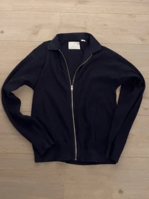 Mörkblå ziptröja  - Snygg mörkblå ziptröja. Tröjan är xs men funkar som S. Tröjan har hel dragkedja framtill, klassisk krage och långa ärmar. Perfekt för dig som gillar enkel och stilren design med en avslappnad passform.