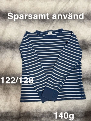 Blåvit randig långärmad topp - En blå långärmad topp med vita horisontella ränder och rund hals. Tröjan har en klassisk passform och är perfekt för en avslappnad stil. .🌸Sparsamt använd. Storlek 122/128