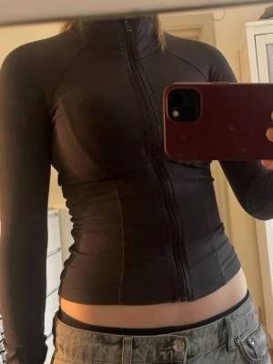 Svart tränings ziptröja med hög krage - Säljer en svart, figurnära ziptröja med hög krage och långa ärmar. Tröjan har en hel dragkedja framtill och är tillverkad i ett stretchigt material som sitter snyggt på kroppen. Perfekt till lager-på-lager och enkel att styla till olika outfits.