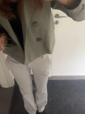 Kort oliv grön trenchcoat - Snygg kort trenchcoat i olivgrönt med dubbelknäppning framtill och klassisk krage. Jackan har en croppad passform och stora knappar som ger en trendig look. Perfekt att slänga över en t-shirt eller hoodie för en chill stil. Från Hm 