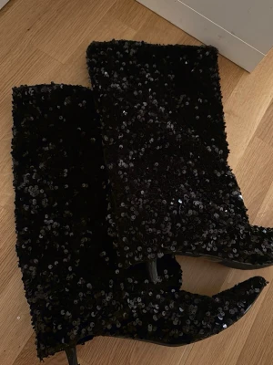 Svarta paljettstövlar med klack - Glittriga svarta stövlar med paljetter och spetsig tå. 