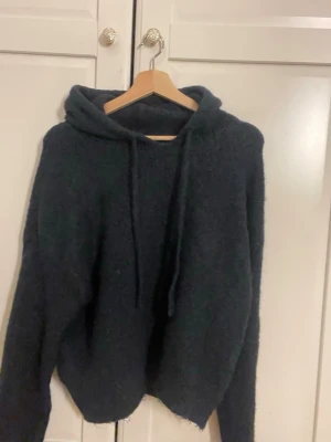 Svart stickad hoodie från Gina Tricot - Mysig svart stickad hoodie från Gina Tricot i storlek M. Perfekt för mysigt overzised look till ett par jeans 
